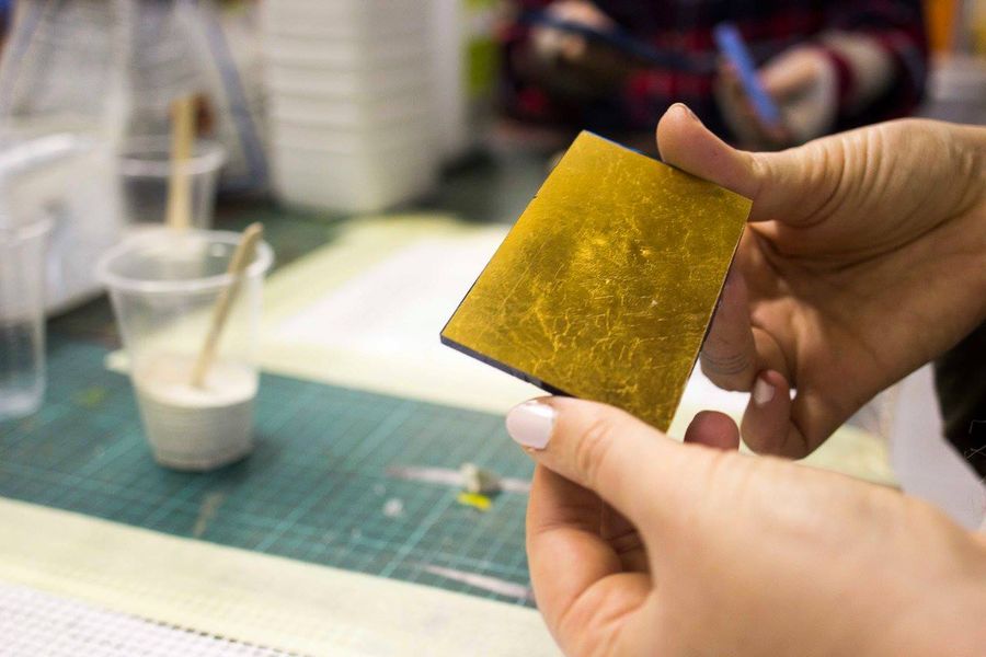 A hand holding a sheet of gold leaf used in mosaic and jewellery detailing