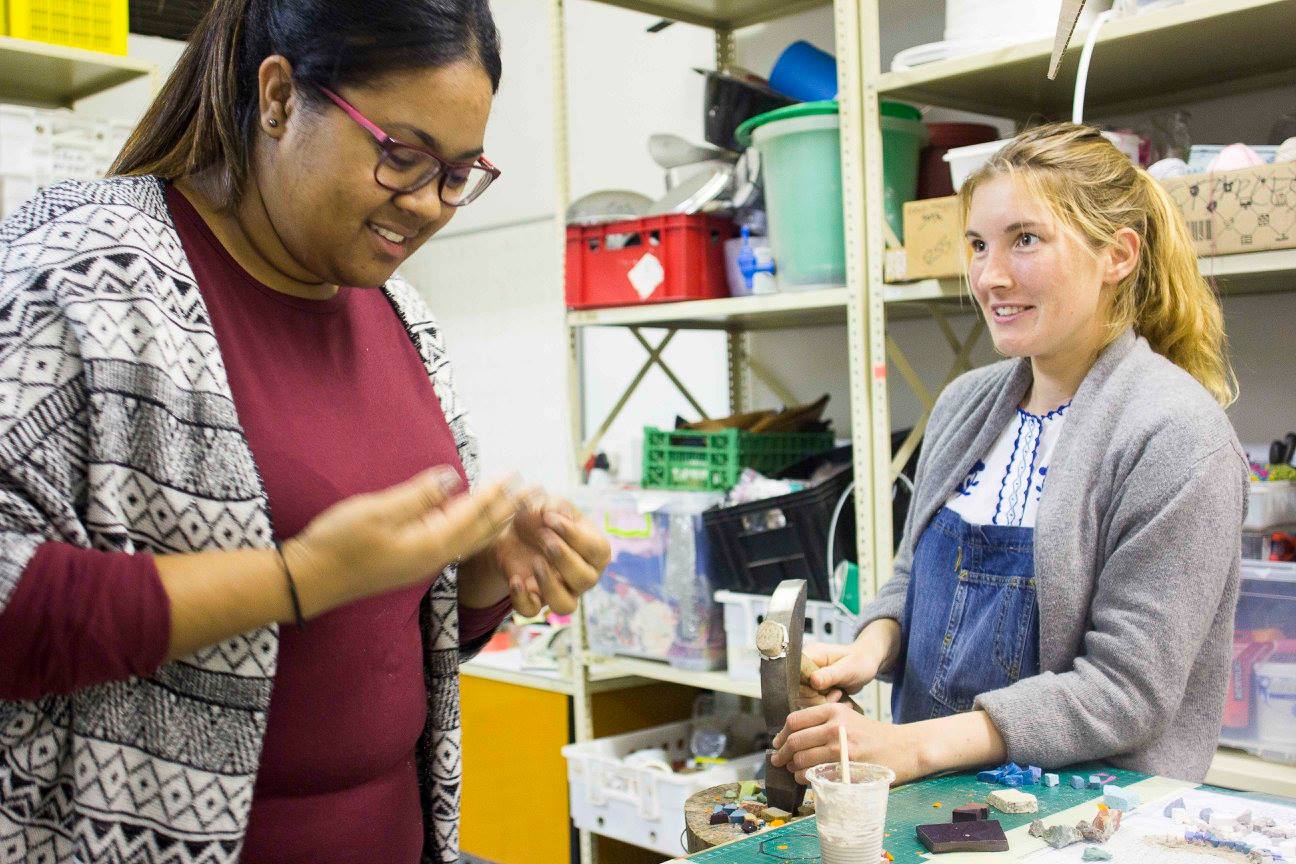 Two workshop participants collaborating closely over a piece of jewellery