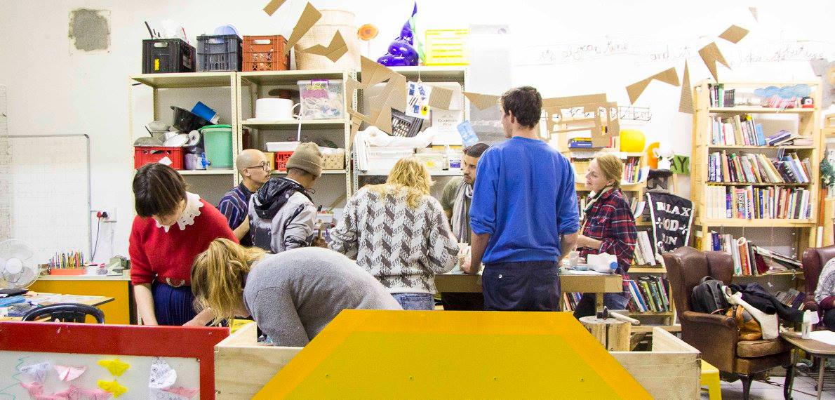 A group of workshop visitors gathered around tables inside the studio